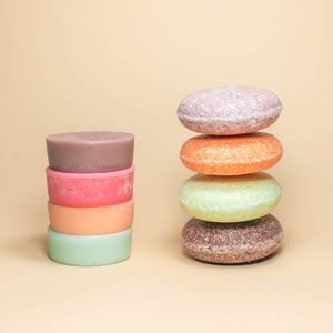 May include: A stack of four round, colorful shampoo bars, next to a stack of four round, colorful shampoo bars.