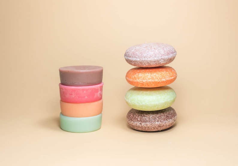May include: A stack of four round, colorful shampoo bars, next to a stack of four round, colorful shampoo bars.