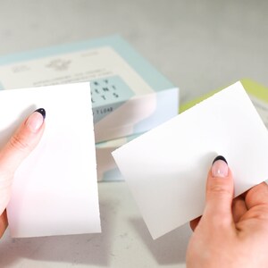 Puede incluir: Dos blocs de papel rectangulares blancos con esquinas redondeadas, sostenidos en manos. Los blocs est&aacute;n en blanco y parecen ser para tomar notas.
