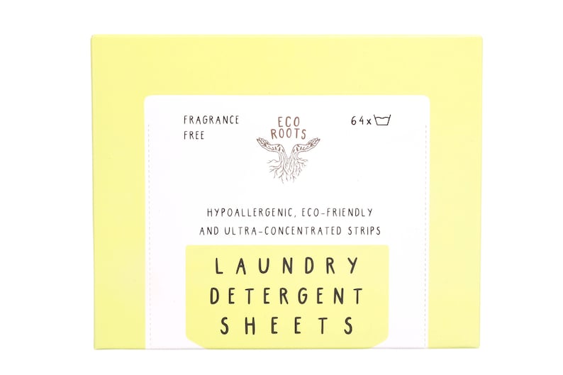 Puede incluir: Una caja amarilla con texto blanco que dice "FRAGRANCE FREE", "ECO ROOTS", "64x", "HYPOALLERGENIC, ECO-FRIENDLY AND ULTRA-CONCENTRATED STRIPS", "LAUNDRY DETERGENT SHEETS". La caja contiene hojas de detergente para la ropa.