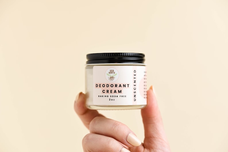 May include: A small glass jar with a black lid containing unscented deodorant cream. The label reads "Eco Roots Deodorant Cream Baking Soda Free 2 oz Unscented".