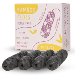 Puede incluir: Una caja de cuatro recambios de hilo dental de bamb&uacute; negro. La caja es rosa y amarilla con el texto "Bamboo Floss Refill Pack", "33 Yards", "30 Metros", "Vegan", "Cruelty-Free", "Recyclable Packaging", y "4x Floss".