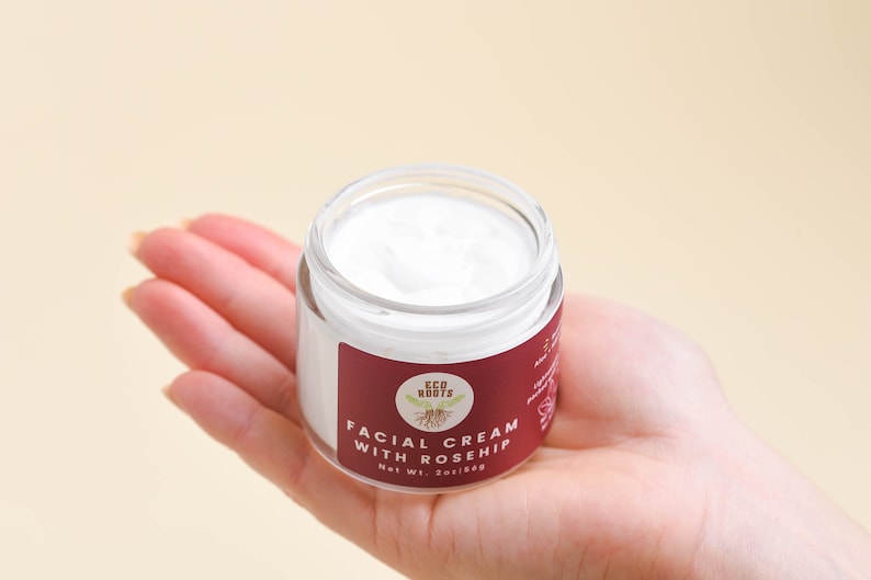 May include: A small white jar of facial cream with a red label that says "ECO ROOTS FACIAL CREAM WITH ROSEHIP Net Wt. 2oz/56g".