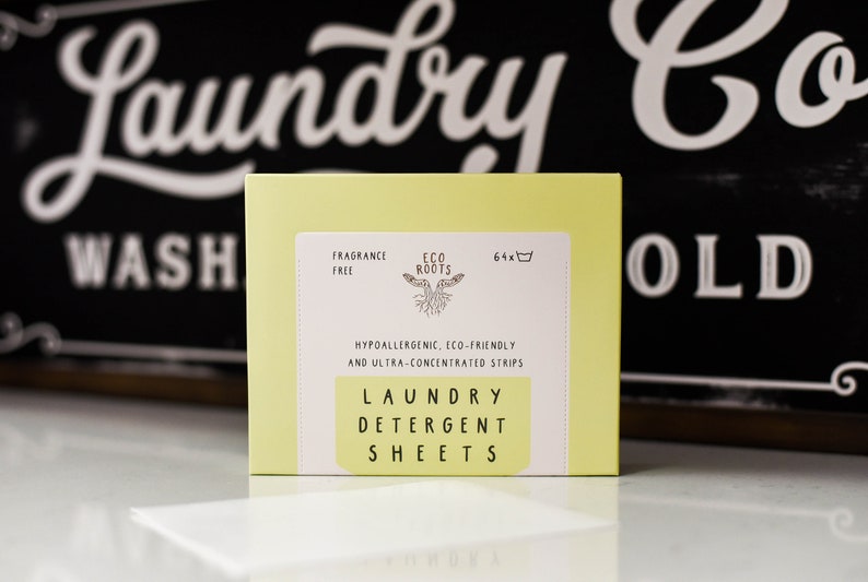 Puede incluir: Una caja amarilla de 64 hojas de detergente para la ropa de Eco Roots. La caja est&aacute; etiquetada como "sin perfume", "hipoalerg&eacute;nica", "ecol&oacute;gica" y "ultra concentrada".