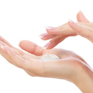 May include: A person's hands applying a white lotion to their palm.