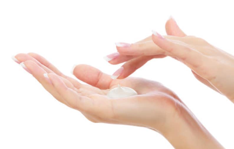 May include: A person's hands applying a white lotion to their palm.