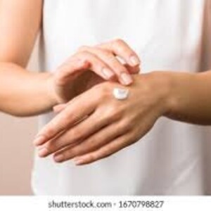 May include: A person's hand applying a dollop of white hand cream to their other hand.