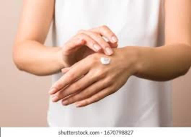May include: A person's hand applying a dollop of white hand cream to their other hand.