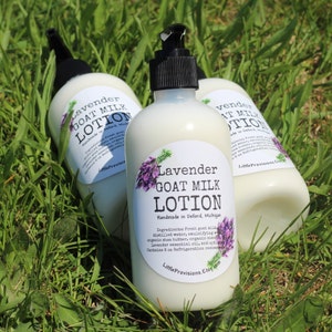May include: Three white bottles of lavender goat milk lotion with a white label that says "Lavender Goat Milk Lotion" and "Handmade in Deford, Michigan". The bottles are sitting on a bed of green grass.