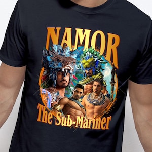 May include: Black t-shirt with a gold graphic of a superhero named "Namor, The Sub-Mariner". The graphic features a collage of four images of the superhero in different poses.