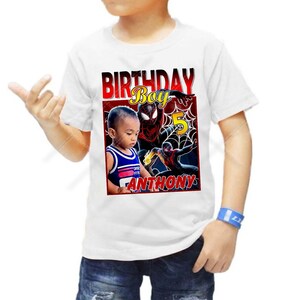 Op de afbeelding: Wit T-shirt met een rode en zwarte Spiderman-afbeelding, het gezicht van een jongen en de tekst "Birthday Boy" en "Anthony".