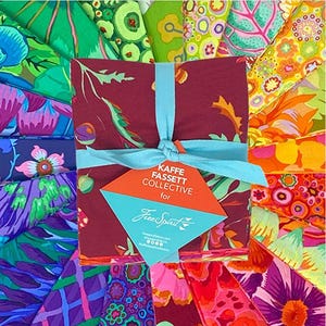 Peut inclure: Un ensemble de carrés de tissu à motifs dans une variété de couleurs, dont le violet, le vert et l'orange. Le tissu est noué avec un ruban bleu clair et comporte une étiquette indiquant "Kaffe Fassett Collective for Free Spirit."