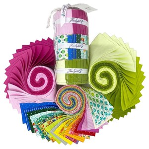 Op de afbeelding: Een verzameling van stofrollen en bundels in verschillende kleuren en patronen, waaronder roze, groen, blauw, geel en wit. De stof is in een cirkel gerangschikt met de tekst "Free Spirit" zichtbaar op de rollen.