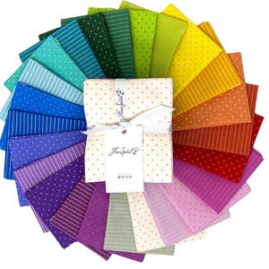 Puede incluir: Un conjunto de 24 cuadrados de tela en un arcoíris de colores, con patrones de lunares y rayas. Los cuadrados de tela están dispuestos en forma de abanico y están etiquetados como "Free Spirit".