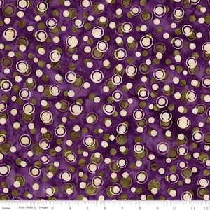 May include: Purple fabric with a pattern of white and olive green circles and dots. The circles have a ring design. The fabric is measured in inches along the bottom edge. The brand is Riley Blake Designs.