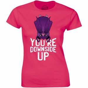 May include: Pink women's t-shirt with a purple cartoon bat hanging upside down and the text "You're Downside Up".