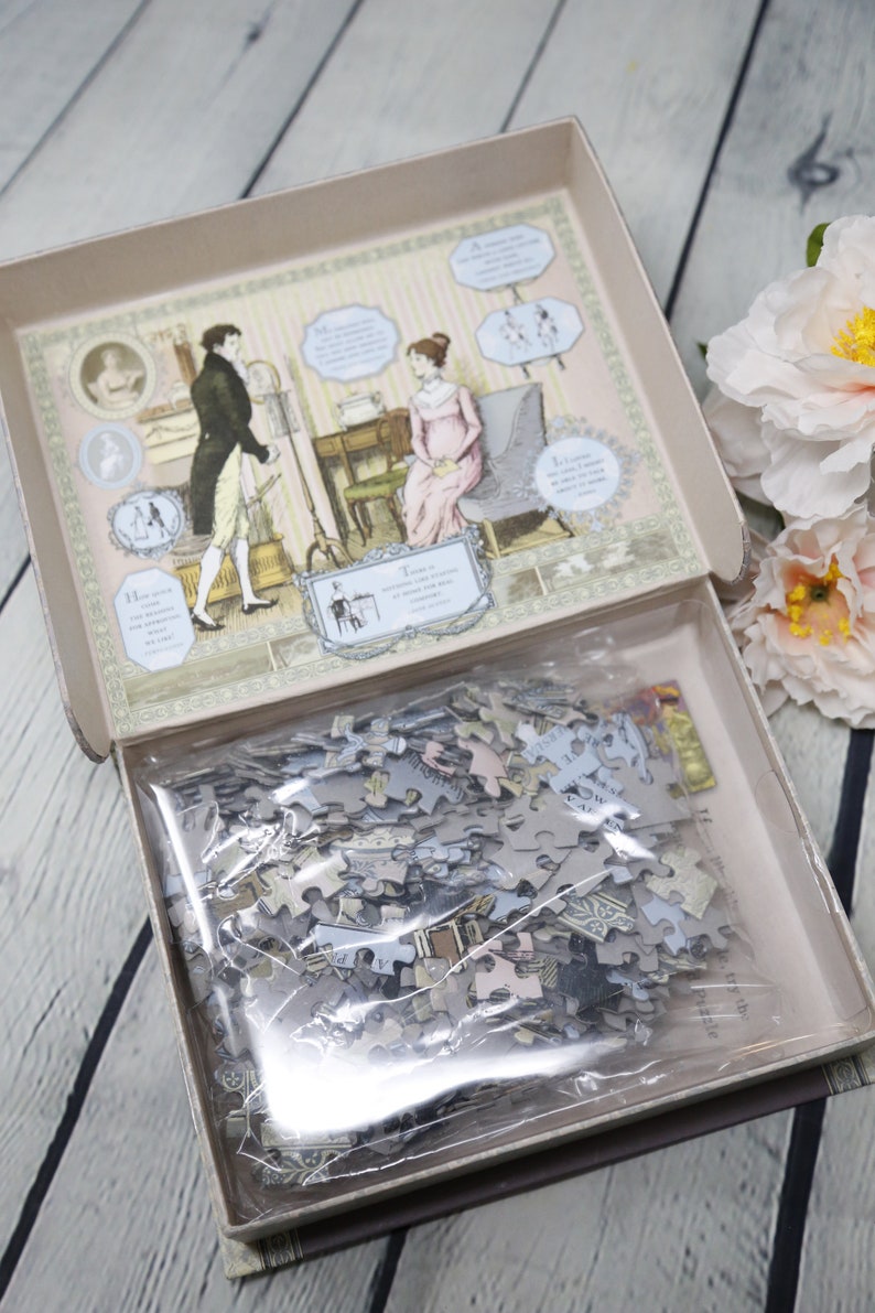 May include: A closed box with a vintage illustration of a couple in a room. The box contains a jigsaw puzzle with a similar design. The puzzle pieces are in a plastic bag.