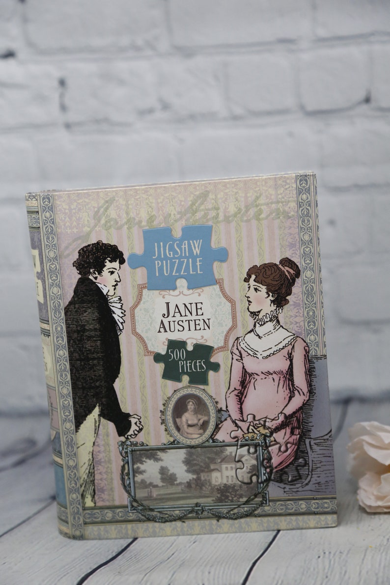 May include: A vintage-style jigsaw puzzle box featuring a couple in period clothing. The box is decorated with a floral pattern and the text "Jigsaw Puzzle Jane Austen 500 Pieces".