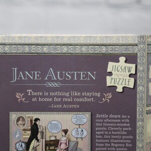 May include: A purple box with a Jane Austen jigsaw puzzle. The box features a quote from Jane Austen, "There is nothing like staying at home for real comfort." The puzzle is 500 pieces and measures 18 inches by 14 inches.