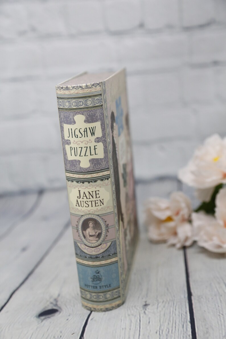 May include: A book-shaped box with a jigsaw puzzle design. The box is decorated with a floral pattern and the text "Jigsaw Puzzle" and "Jane Austen".