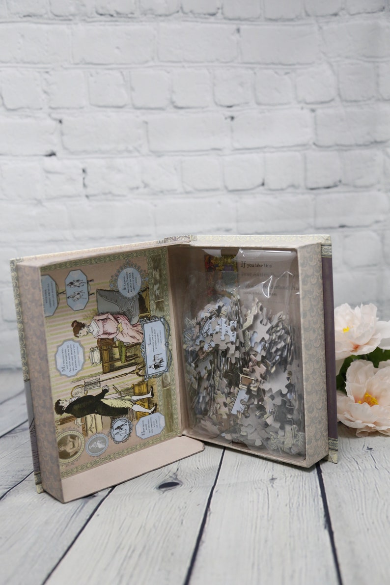 May include: An open box with a vintage-style illustration of a couple on the inside. The box contains a jigsaw puzzle with a plastic bag. The box is on a wooden surface.
