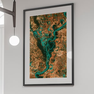 May include: A framed abstract print featuring a swirling, teal-colored river flowing through a brown and orange landscape.