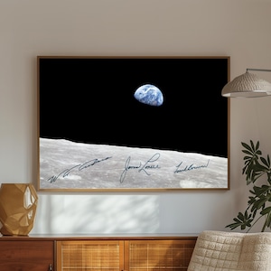 May include: A framed print of the Earth rising over the lunar surface, a famous photograph from the Apollo 8 mission. The image features the Earth in blue and white against a black sky, with signatures of the astronauts.
