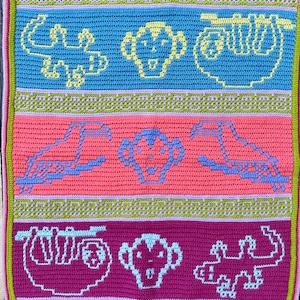 Puede incluir: Una manta de ganchillo con un patrón geométrico colorido que presenta varios animales, incluyendo un perezoso, un mono y un cocodrilo. La manta está hecha con diferentes tonos de rosa, morado, azul, verde y amarillo.