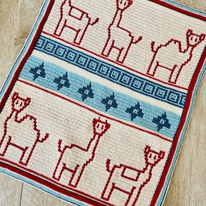 May include: A white crocheted baby blanket with a red border and a pattern of llamas. The blanket has a blue and white geometric pattern in the middle.