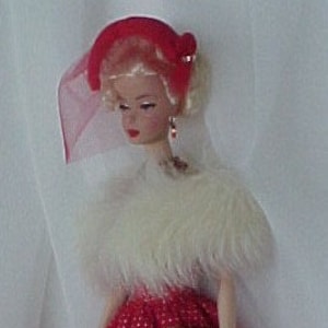 Könnte beinhalten: Eine Puppe in einem rot-weißen Kleid mit einem weißen Pelzschal und einem roten Hut. Die Puppe hält eine braune Handtasche.