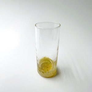 May include: A clear glass drinking glass with a gold-colored bottom. The glass is empty.