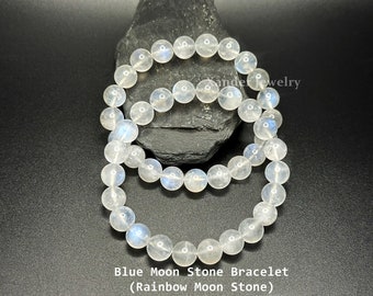 May include: Two stretch bracelets composed of translucent, round, polished moonstone beads with subtle blue iridescence. The text Xander Jewelry, Blue Moon Stone Bracelet (Rainbow Moon Stone) is visible on the image.