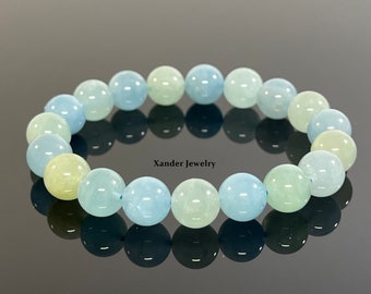 May include: A bracelet made of light blue, green, and yellow aquamarine beads. The bracelet is made of 18 beads and is approximately 7 inches in length. The beads are all round and have a smooth, polished finish.