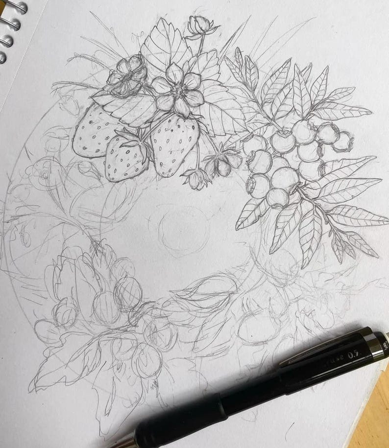 K&ouml;nnte beinhalten: Eine Bleistiftskizze eines Kranzdesigns mit Erdbeeren, Blaubeeren und Bl&auml;ttern. Die Zeichnung ist detailliert mit Schattierungen und Umrissen, und ein schwarzer Stift befindet sich im Vordergrund.