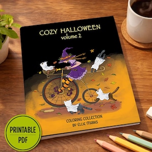 May include: A colouring book titled COZY HALLOWEEN volume 2 by Ellie Marks. The cover features a purple-clad witch riding a bicycle with cats in ghost costumes, surrounded by autumn leaves. A green circular badge reads PRINTABLE PDF.