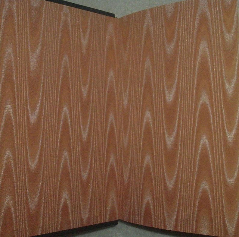 K&ouml;nnte beinhalten: Zwei Tafeln mit Holzmaserung. Die braune Oberfl&auml;che weist ein wellenf&ouml;rmiges, vertikales Design in einer helleren Farbe auf, wodurch ein strukturierter Look entsteht. Die Tafeln treffen sich in einem rechten Winkel und zeigen den Verlauf des Musters.