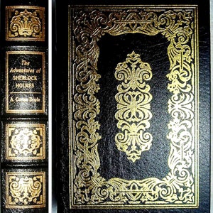 Puede incluir: Un libro de tapa dura negro titulado "The Adventures of Sherlock Holmes" de A. Conan Doyle. El libro tiene una cubierta negra con detalles dorados ornamentados, incluyendo un borde decorativo y un diseño central. El lomo también presenta letras y adornos dorados.