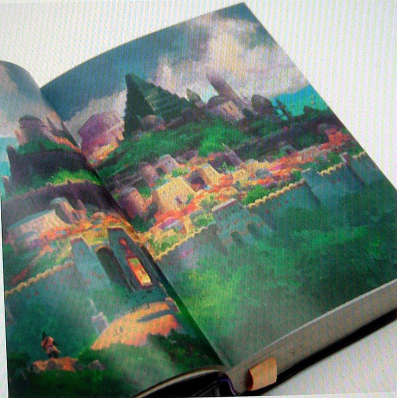 May include: An open book with a colorful illustration of a city on a hill. The city is made up of buildings with different colors and textures. The book is open to a page with a close-up view of the city.