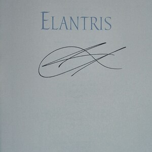 May include: A book titled "Elantris" with a black ink signature on the front cover.