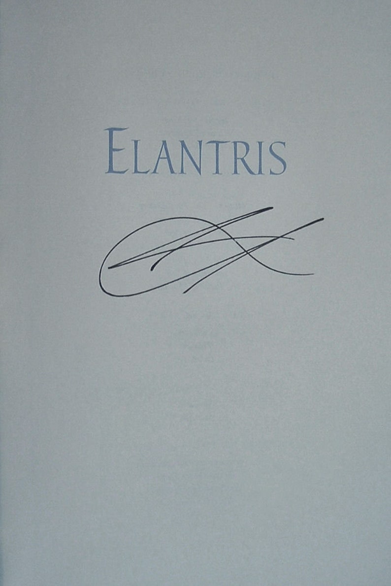 May include: A book titled "Elantris" with a black ink signature on the front cover.