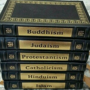 May include: A stack of six black books with gold lettering and accents. The titles on the spines read: Buddhism, Judaism, Protestantism, Catholicism, Hinduism, and Islam. The top book has an ornate gold border.