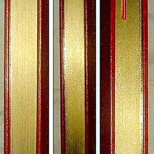 May include: A close-up of a book with a red leather cover and gold-gilded edges. The pages are gold, and a red ribbon bookmark is visible. The book's spine is also red.