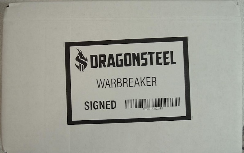 May include: A white box with a black label that says "DragonSteel Warbreaker Signed" with a barcode and a logo of a dragon with an "S" in the middle.