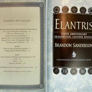May include: A book cover for the tenth anniversary Dragonsteel Leather Edition of the fantasy novel "Elantris" by Brandon Sanderson. The cover features a silver dragon on a black background with the title "Elantris" in gold lettering.