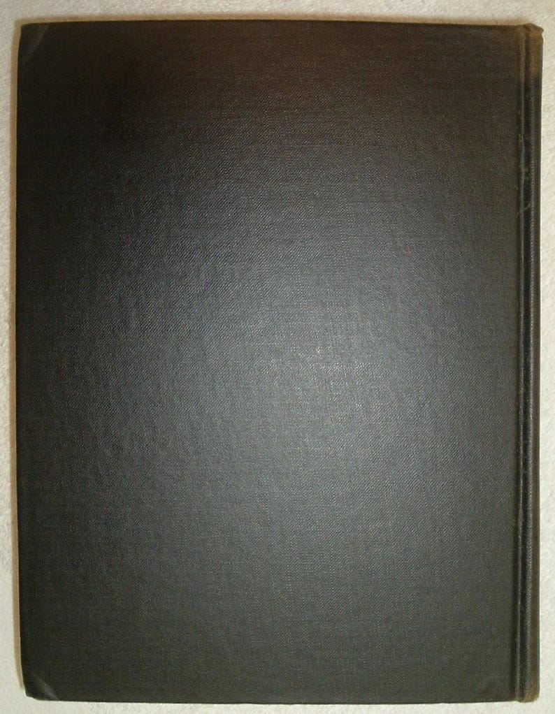 May include: A close-up of a book cover. The cover is a solid, dark charcoal color with a textured, slightly rough surface. The spine is visible on the right side, also dark, with a slightly different texture. The edges of the cover are slightly worn.