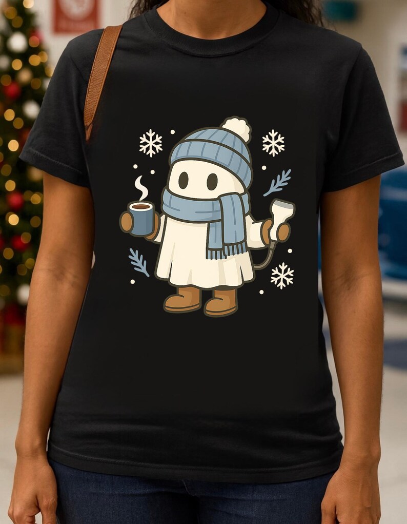May include: Black t-shirt featuring a cartoon character dressed for winter. The character wears a blue hat, scarf, and boots, holding a mug of hot beverage and a medical device. Snowflakes and sprigs are also in the design.