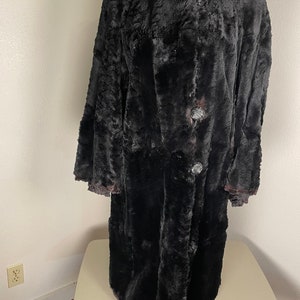 May include: A long black faux fur coat with a collar and button closure.
