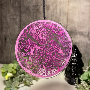 May include: A pink and black abstract design ornament with a black string for hanging.