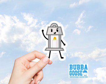 May include: A die-cut sticker featuring a cartoon lantern character with a gray frame, a white candle with a yellow flame, and black stick limbs. The character has a smiling face with one raised arm. The sticker is held against a blue sky background.