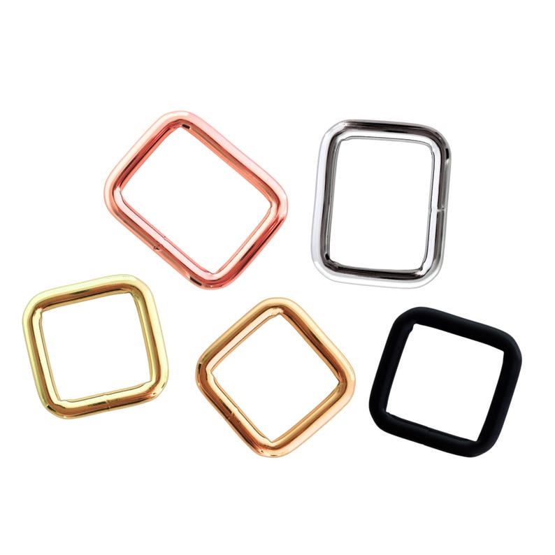 Peut inclure: Cinq anneaux carr&eacute;s en m&eacute;tal de diff&eacute;rentes couleurs : or rose, argent, or, bronze et noir. Ces anneaux sont probablement utilis&eacute;s pour l'artisanat, la fabrication de sacs ou d'autres projets de bricolage. Les anneaux ont une finition lisse et polie.